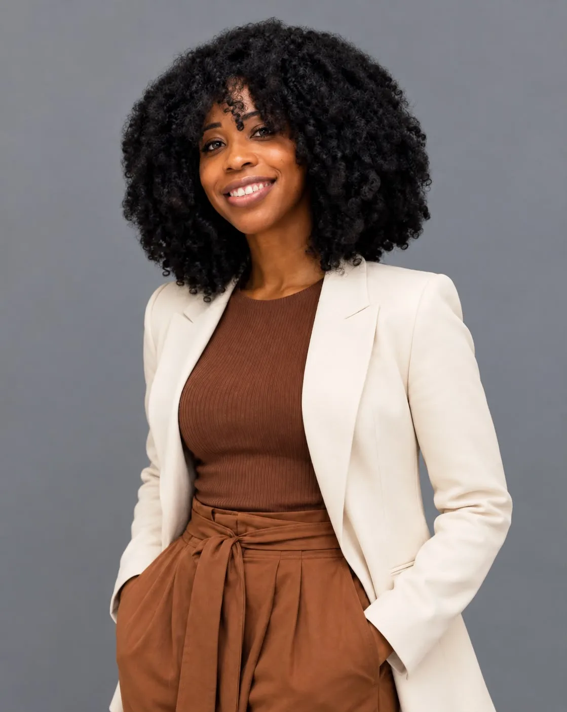 Dr. Yanique L. Rolingson, founder of S.N.A.P. Academy, in a cream jacket, smiling at the camera with one hand in her pocket.
